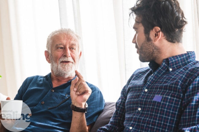 An elderly man and his son having a chat over a cup of tea
