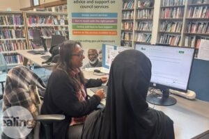 member of staff giving assistance to a customer at the community hub in Acton Library