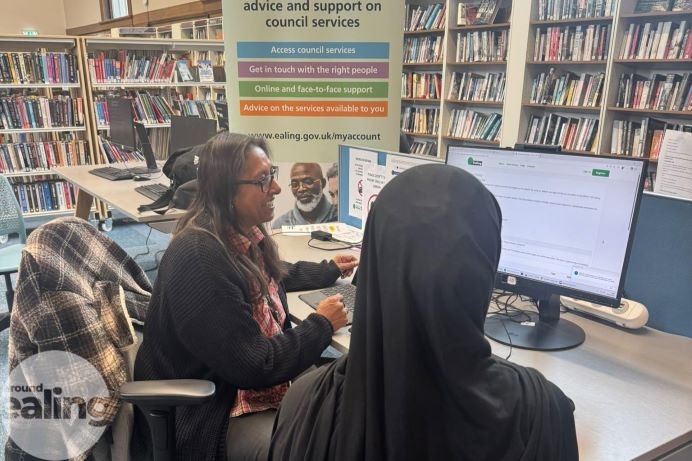 member of staff giving assistance to a customer at the community hub in Acton Library