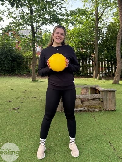 Teacher outdoors smiling and holding a ball
