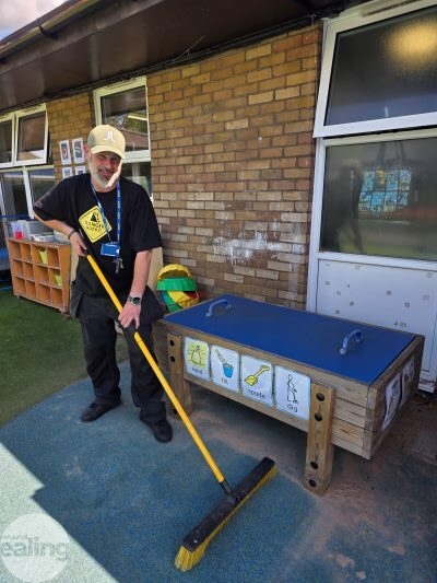 School caretaker outdoors sweeping