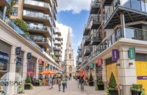A high street with people walking down it and a church in the distance