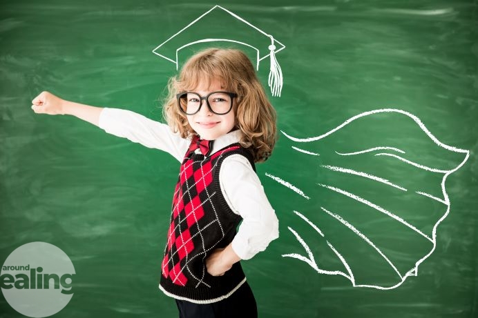 child in hero pose in front of a blackboard